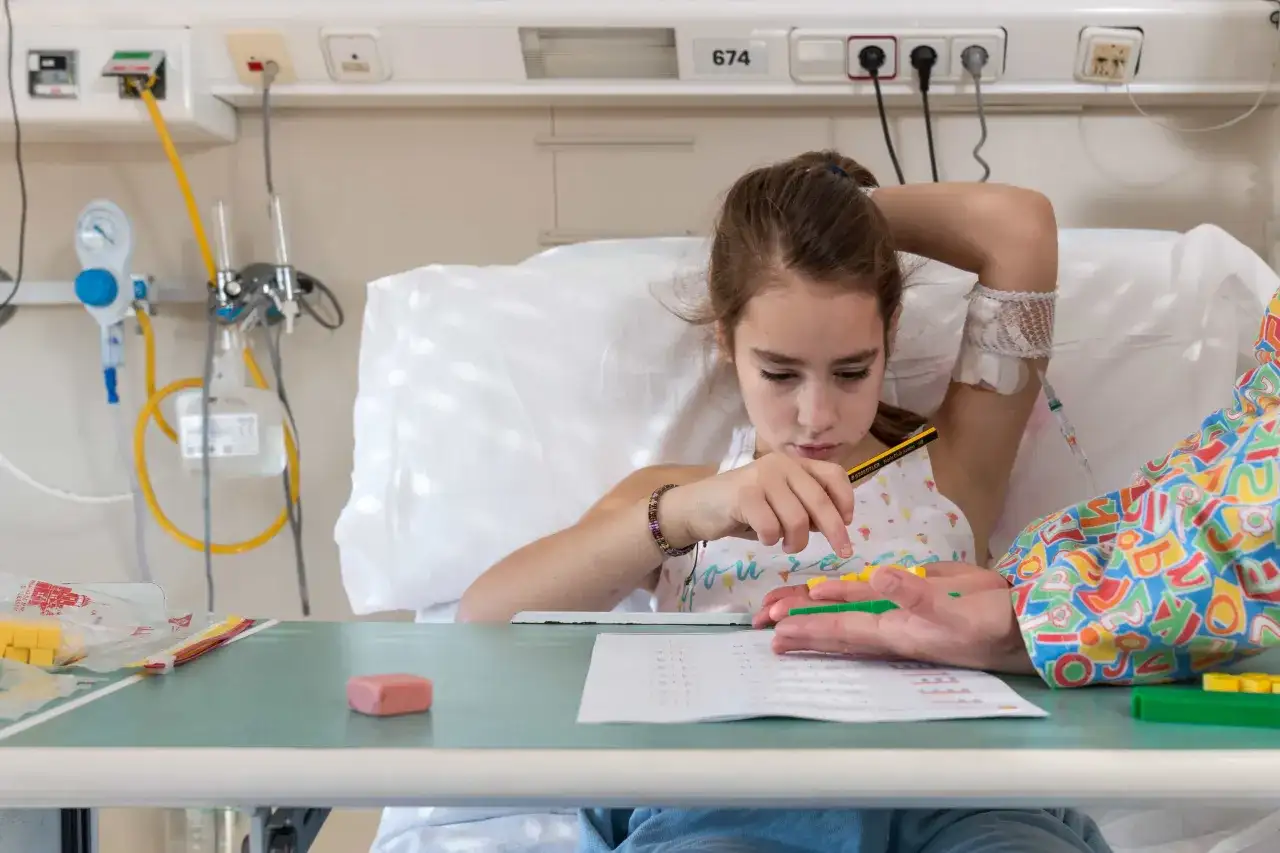 Niña en cama de hospital, con vía intravenosa, jugando con bloques. Un intento de combatir el síndrome de hospitalismo.